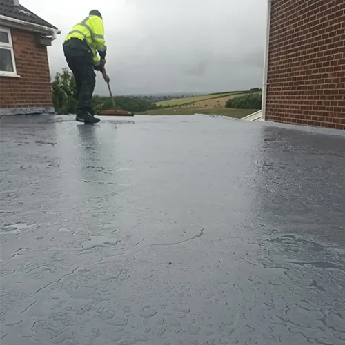A man with a broom on a flat roof.